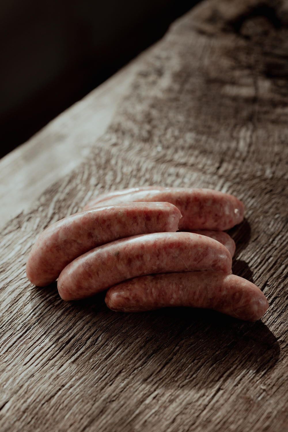 Raw sausages on a wooden surface