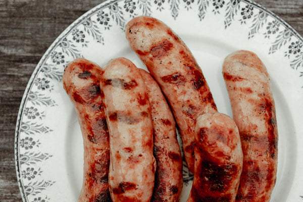 Grilled sausages on a decorative plate with a floral pattern.