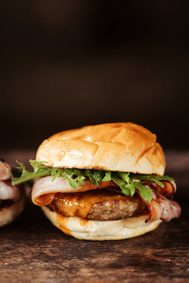 Delicious-looking burger with lettuce and sauce on a wooden surface